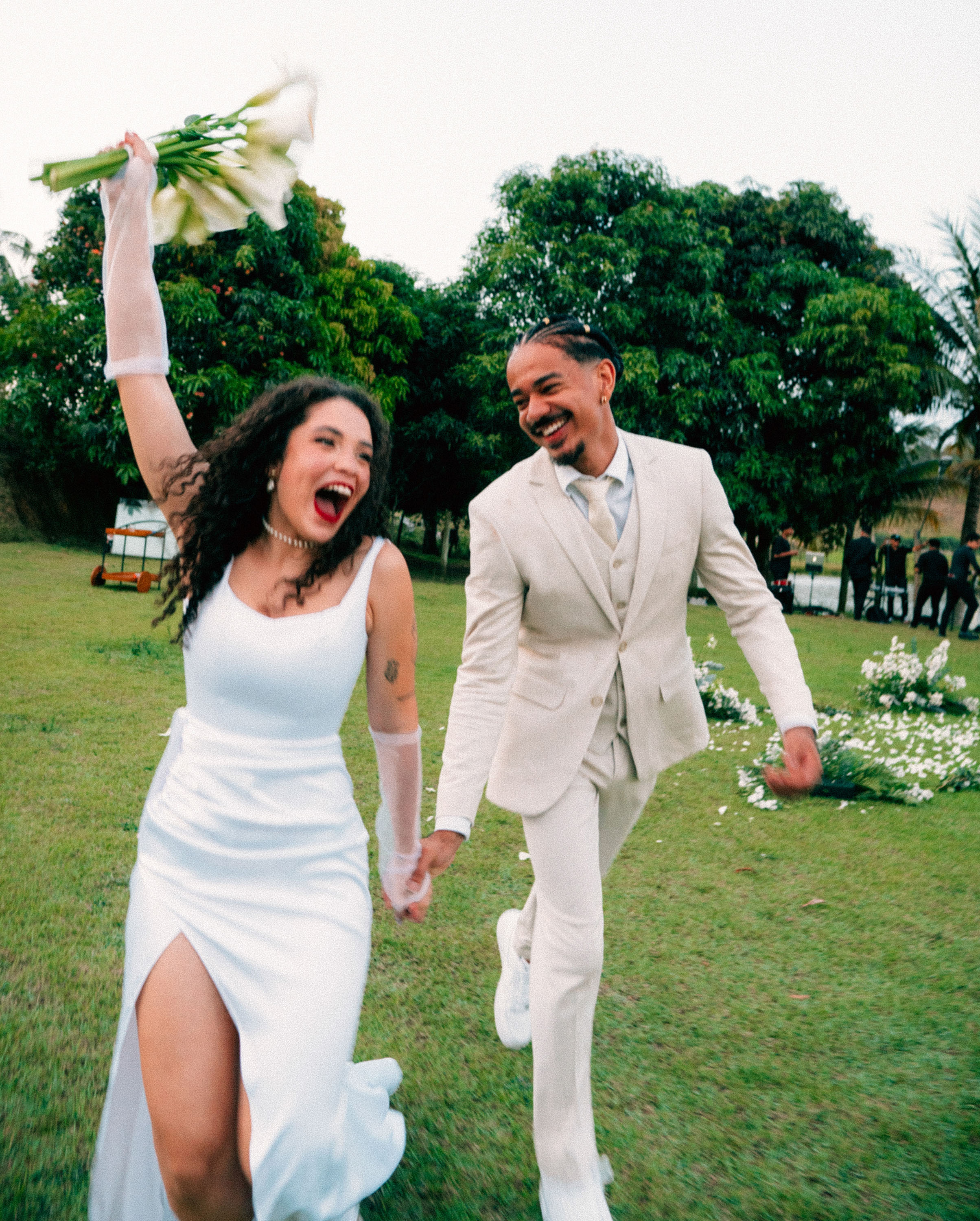 Noiva correndo com buquê de lírios — casamento ao ar livre em jardim