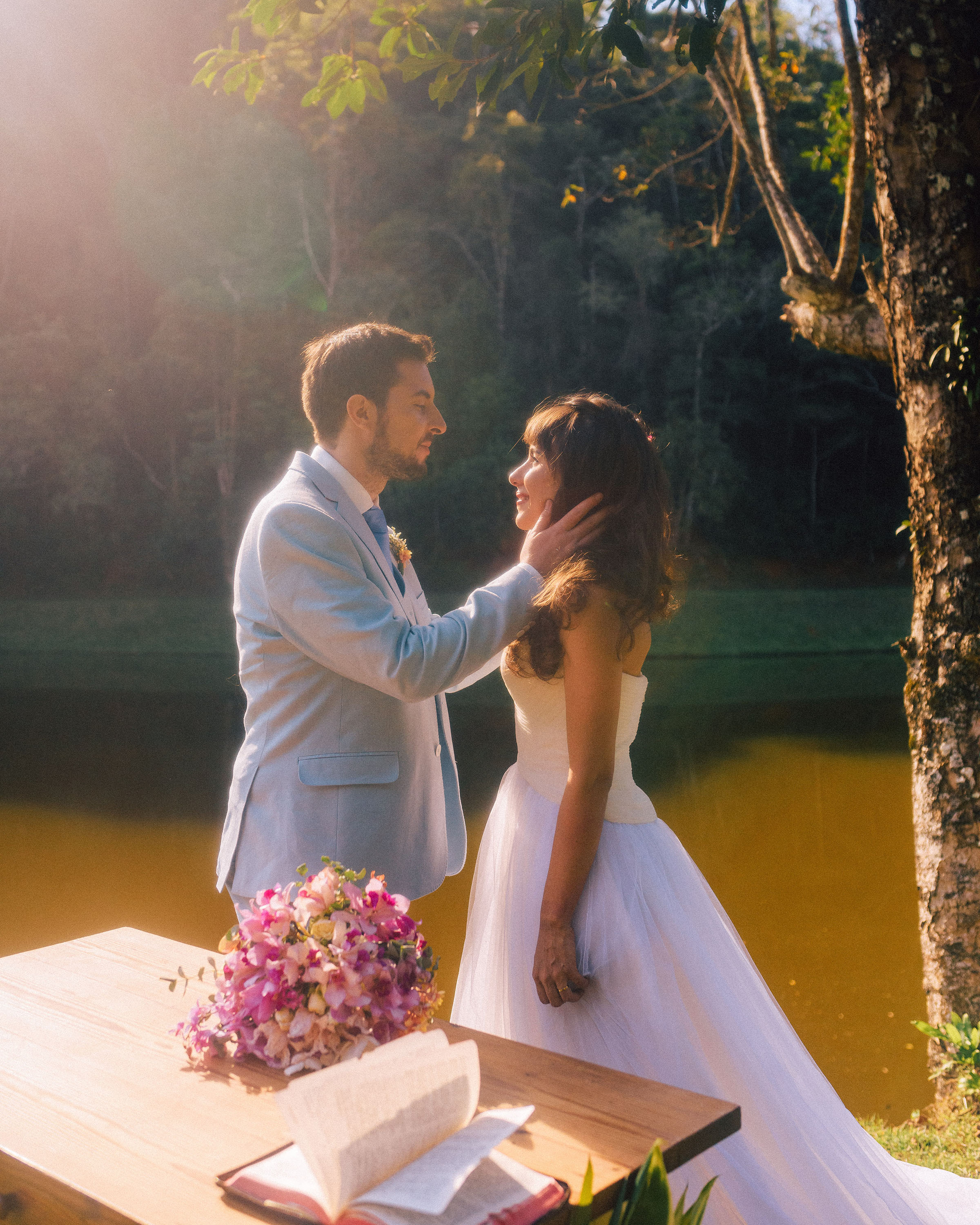 Casal no altar à beira do lago no pôr do sol — cerimônia intimista