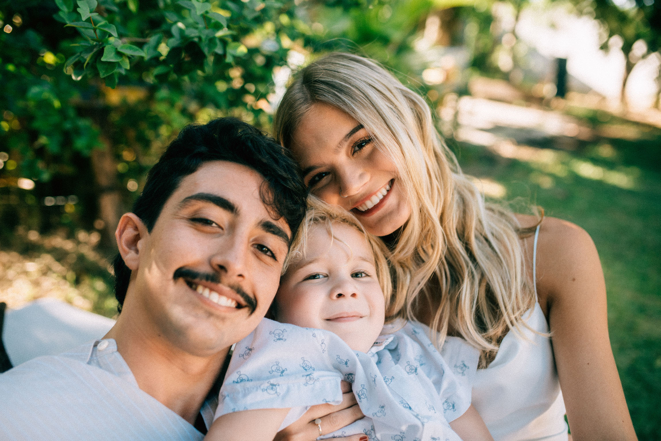 Família com casal e criança na natureza sorrindo